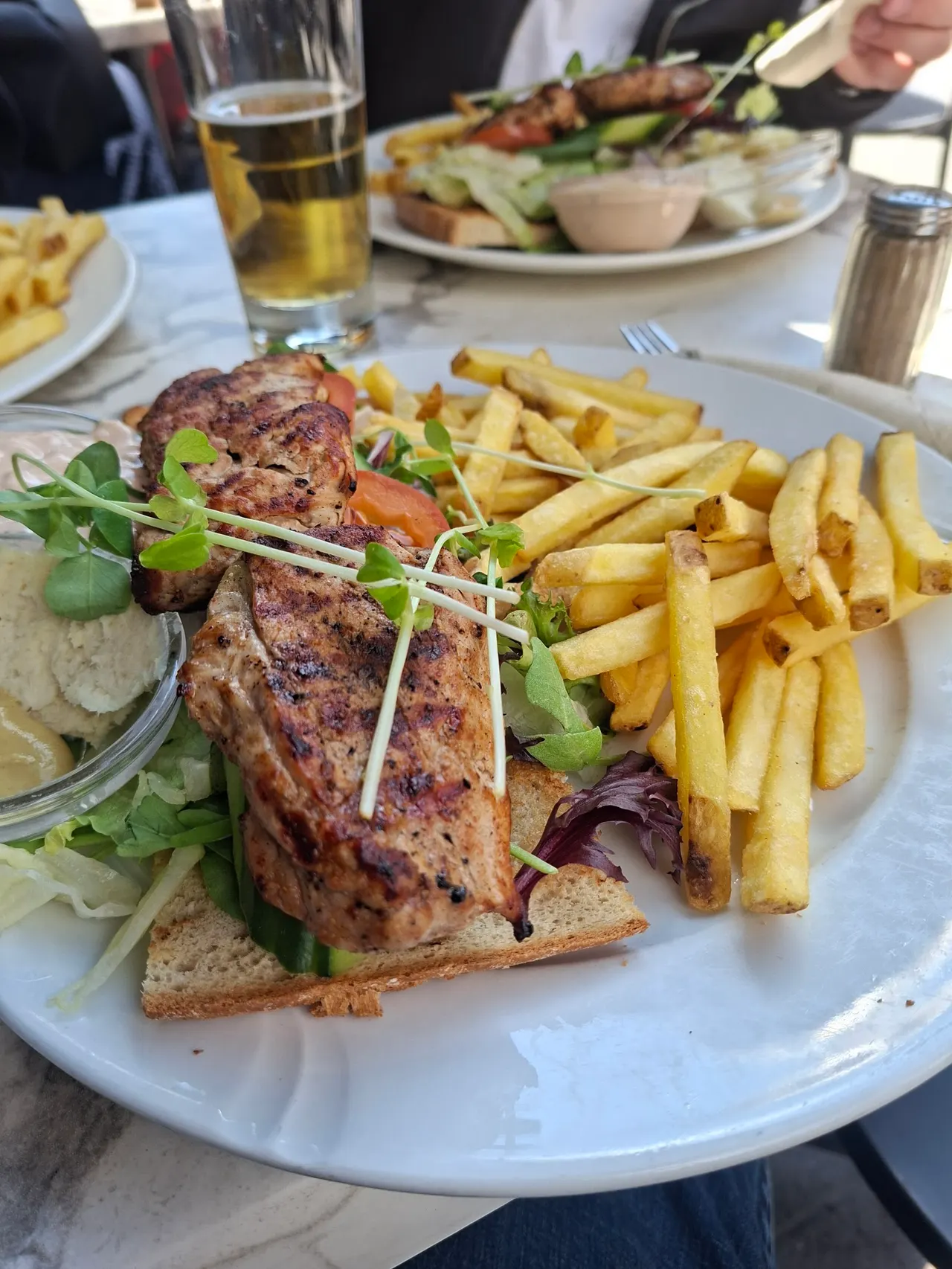 Grillad kötträtt med pommes och sallad på uteserveringen
